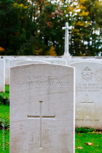 Grave of a Soldier of the Great War in Commonwealth War Graves Commissions (CWGC) Sanctuary Wood Cemetery with a Cenotaph in the background.