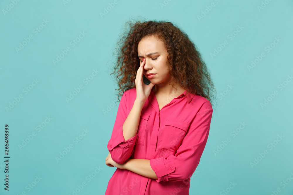 Portrait of dissatisfied tired african girl in casual clothes crying, wiping tears isolated on blue turquoise wall background in studio. People sincere emotions, lifestyle concept. Mock up copy space.