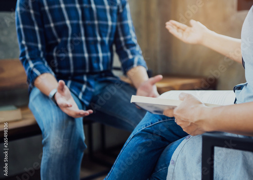 woman holding book in hand while talking with young man friends in works place , copy space.
