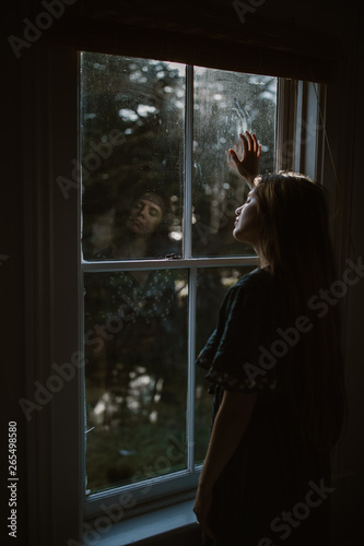 sad woman looking out window in home