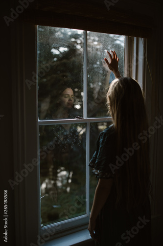 sad woman looking out window in home