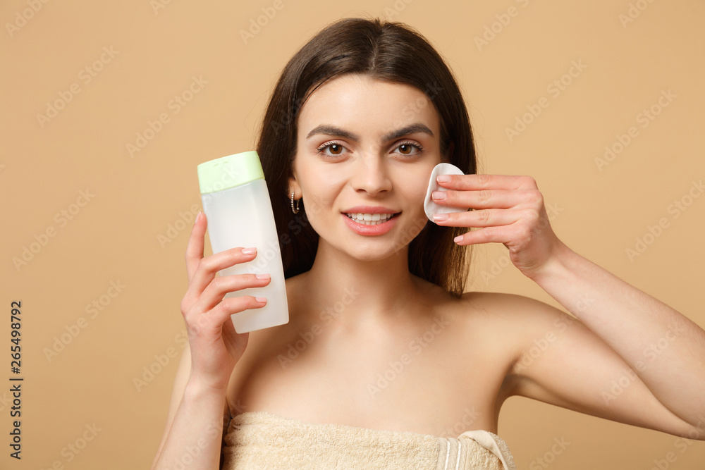 Close up brunette half naked woman 20s with perfect skin, removing nude make up isolated on beige pastel wall background, studio portrait. Health care cosmetic procedures concept. Mock up copy space. Close up brunette half naked woman 20s with perfect skin, removing nude make up isolated on beige pastel wall background, studio portrait. Health care cosmetic procedures concept. Mock up copy space.