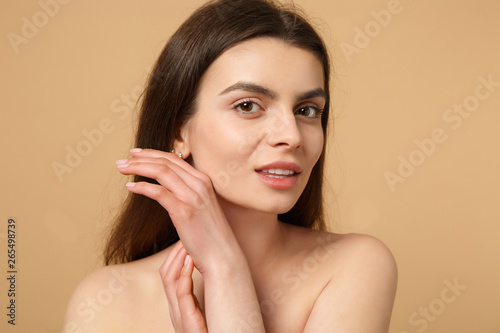 Close up brunette half naked woman 20s with perfect skin, nude make up isolated on beige pastel wall background, studio portrait. Skin care healthcare cosmetic procedures concept. Mock up copy space.
