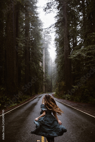 woman in blue dress on road in forest redwoods