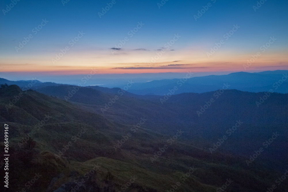 view of the hill around with soft fog with colorful yellow low light in the sky background, sunrise at top mountain, Tan Pha Tey Wor Da View Point, Phu Langka Forest Park, Phayao, Thailand.