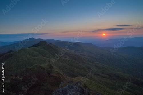 Mountain view morning above many hills and green forest around with soft fog with colorful red sun light in the sky background  sunrise at top of Phu Langka Forest Park  Phayao  Thailand.
