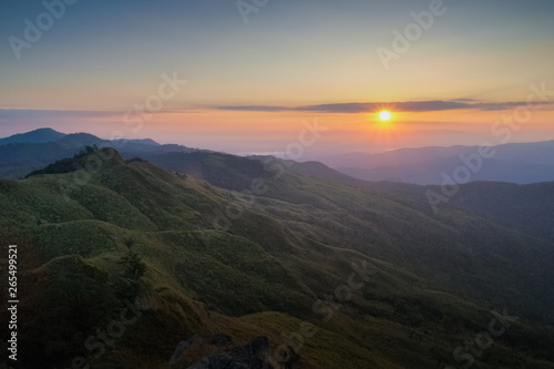 Mountain view morning above many hills and green forest around with soft fog with colorful red sun light in the sky background  sunrise at top of Phu Langka Forest Park  Phayao  Thailand.