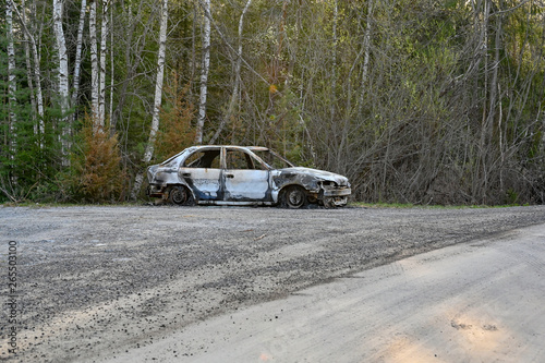 a burnt down car at a gravel road