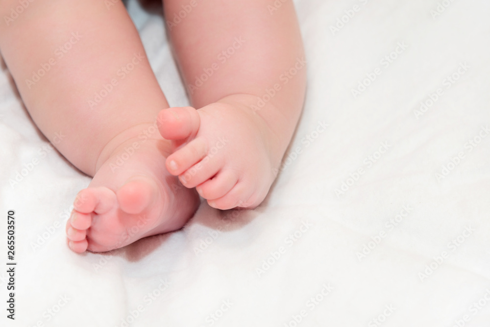Feet newborn baby on a white bedspread. Small baby legs close up. Feet newborn baby on a white bedspread. Small baby legs close up.