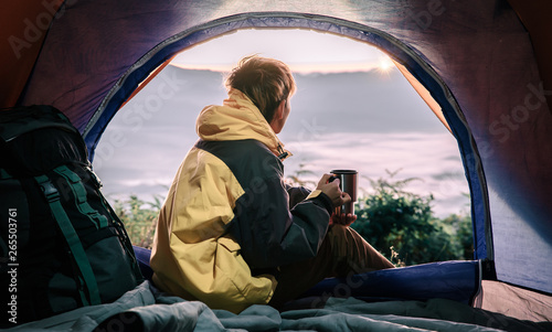 young tourist man holding coffee cup in the tent in morning enjoying the leisure and freedom.