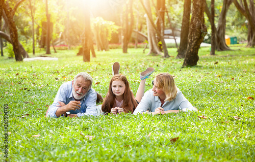 Happy family lying down on green grass in the park and in the summer day with nature background