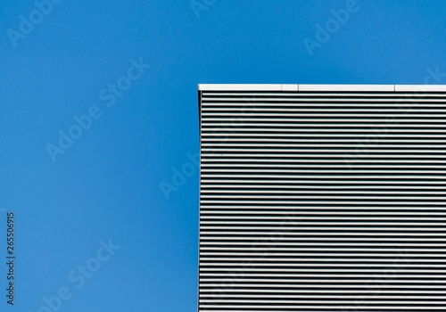 striped wall of a gray tall building against a blue clear sky