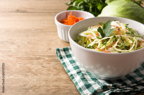 Coleslaw salad in white bowl on wooden table