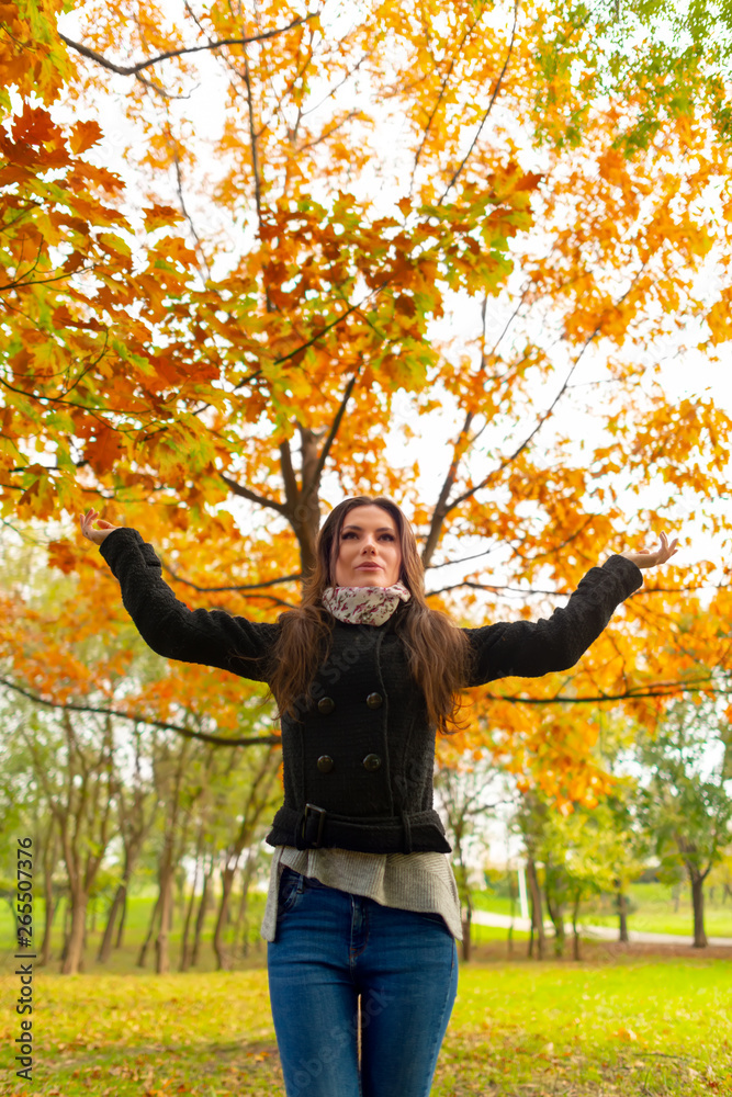 Beautiful girl in park fall scenery, welcoming the autumn season, looking up. Gorgeous young woman outdoors, in a warm sunny day. Body shot in natural light, retouched, vibrant colors Beautiful girl in park fall scenery, welcoming the autumn season, looking up. Gorgeous young woman outdoors, in a warm sunny day. Body shot in natural light, retouched, vibrant colors