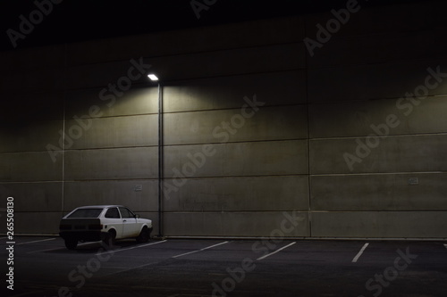 Carro branco em estacionamento de noite. Iluminação publica. Iluminação do estacionamento de shopping  photo