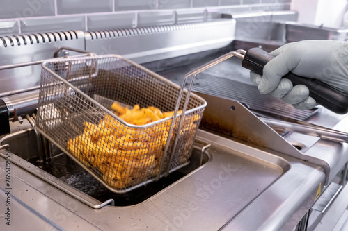 French fries prepared in hot oil in special metal grill photo