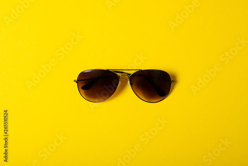 Sunglasses fashion style on yellow background, top view