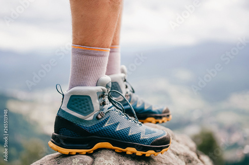 Mood photo of male legs wearing sportive hiking shoes with strong protective sole. Mens legs in trekking footwear for mountain travel standing on stone outdoor at nature on abstract background. photo