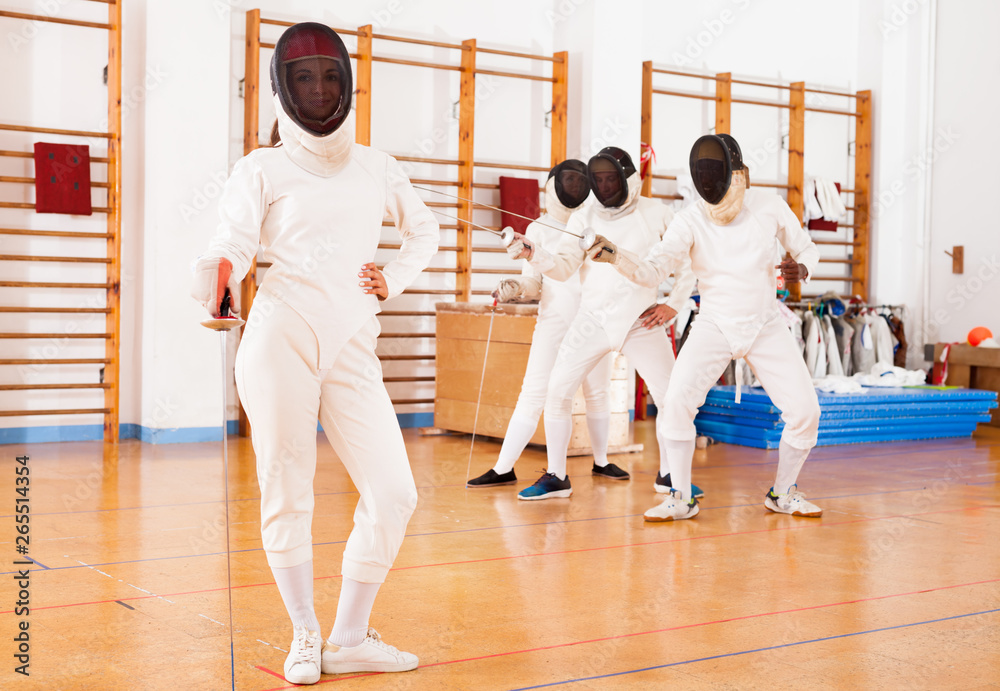 Young female in mask with foil at fencing workout