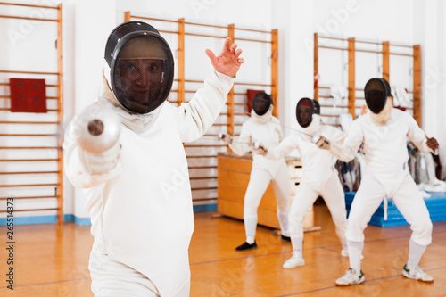 Sporty young man fencer practicing effective fencing techniques in training room