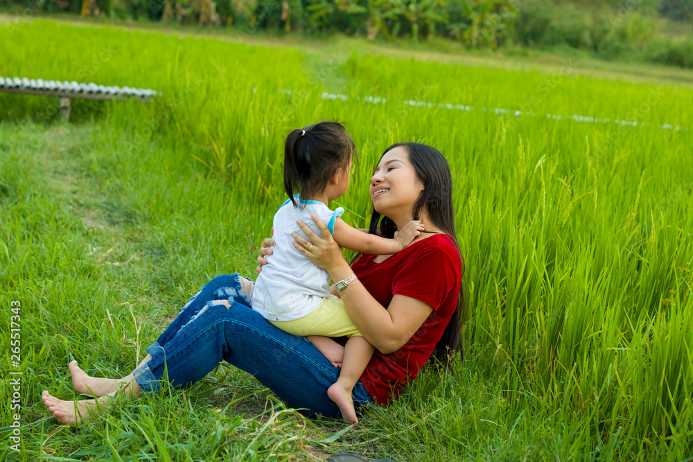Lifestyle portrait mom and daughter in happiness at the outside in the meadow, Funny Asian family in a rice field.