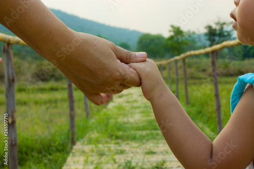 Parent holds the hand of a little child green background, soft focus