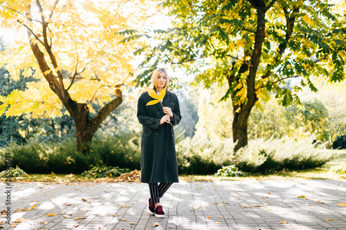 portrait of full-length pensive girl in black coat with Frond in hand