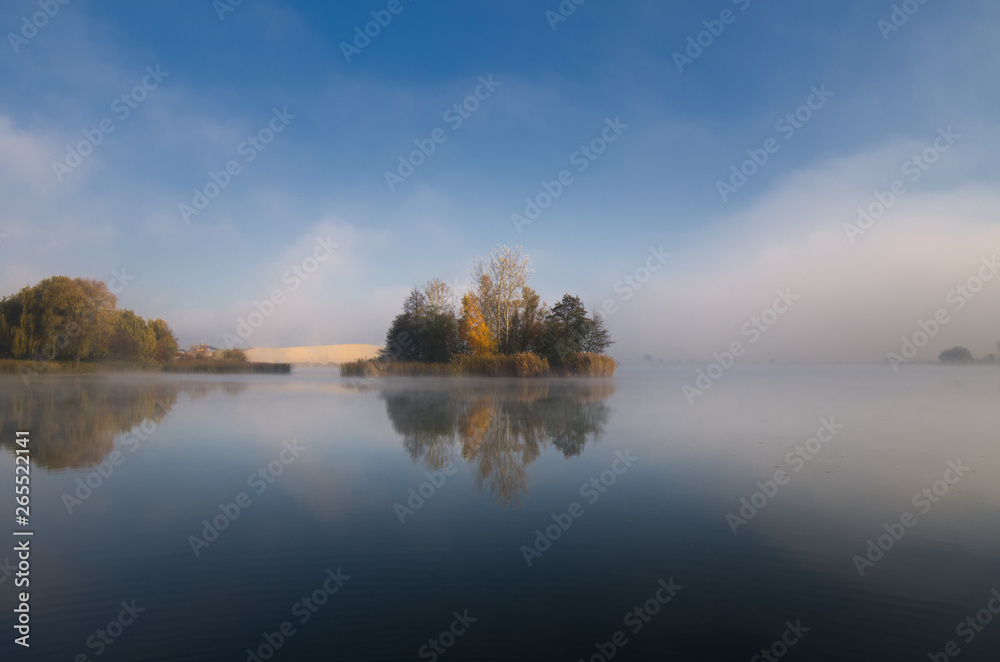 Island on the lake on an autumn morning reflected in the water