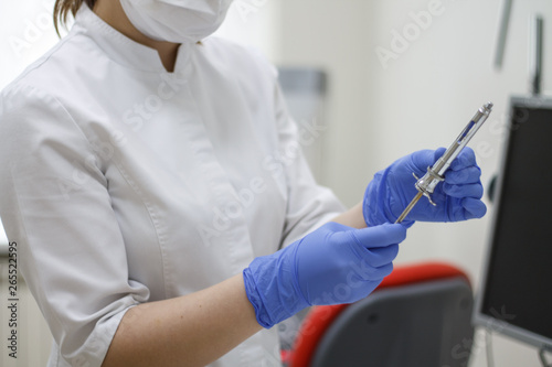 dental instruments in hand blue glove syringe on dentistry background © Juli Puli