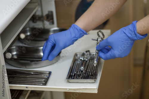 hands in blue gloves holding dental tools from the locker Bura syringe