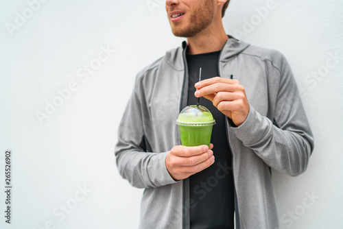 Healthy young man drinking green juice smoothie cup as weight loss detox meal replacement diet. Spinach protein shake for morning breakfast.
