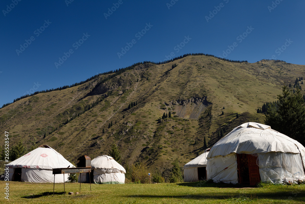 Yurts in campground at Kaindy Lake with landslide prone Kungey Alatau mountains Kazakhstan