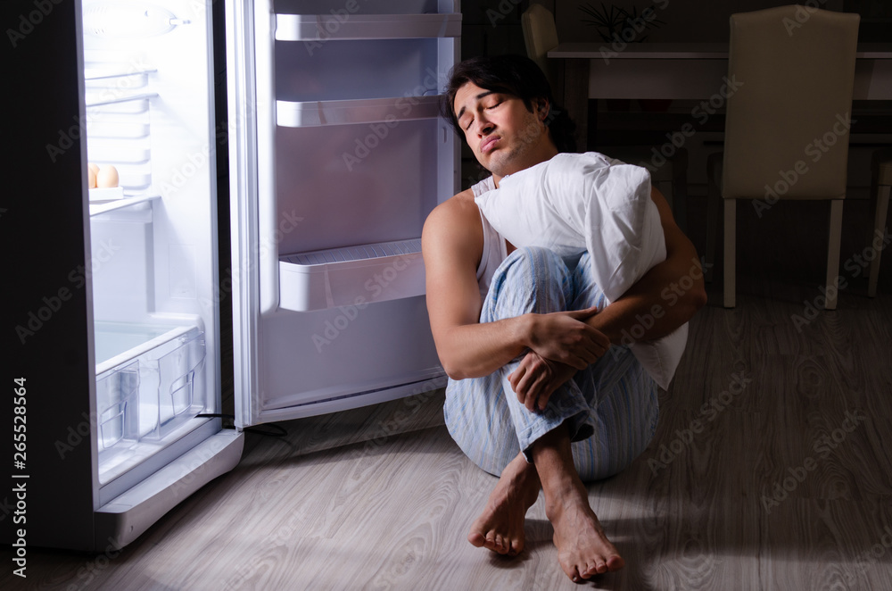 Man breaking diet at night near fridge