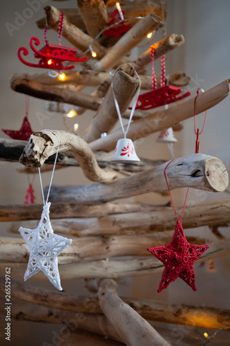 A wooden Christmas tree with white fairy lights and red & white decorations hanging from it