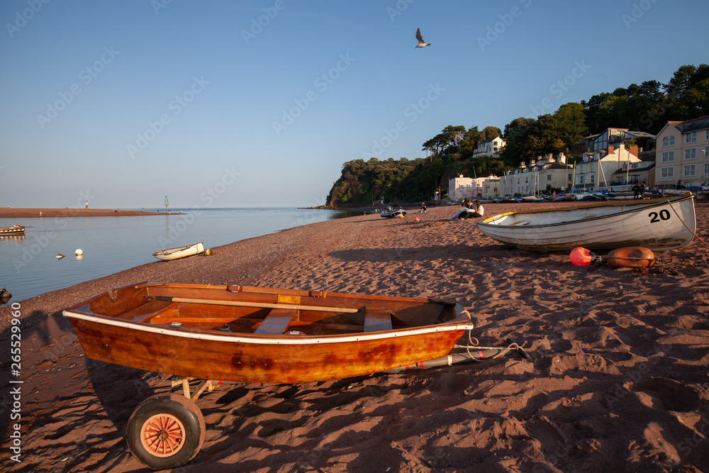 Fototapeta premium An empty beach with a wooden row boat sitting on a trailer on a sunny evening