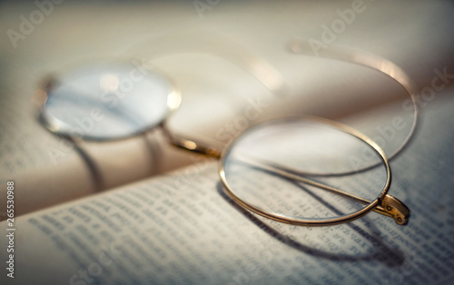 Vintage Eyeglasses and antique old book. Retro style. Concept idea on the topic of science, education, history, etc. Shallow depth of field, selective focus.