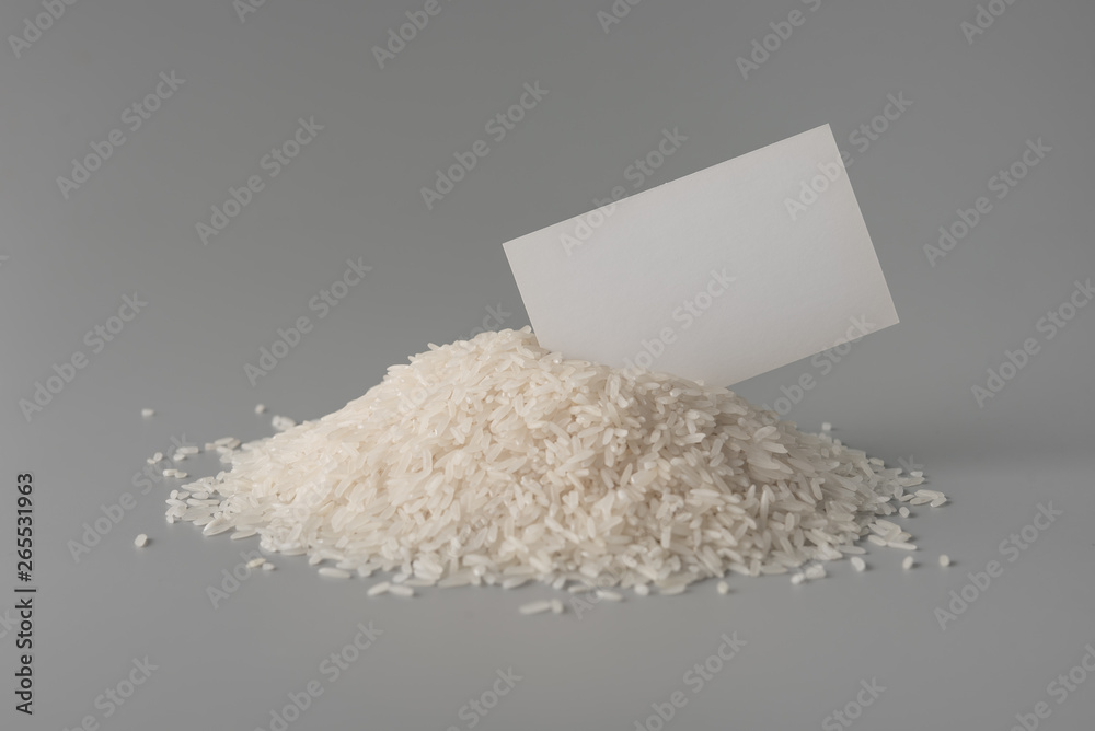 Pile of uncooked rice grains with blank label on grey background Pile of uncooked rice grains with blank label on grey background