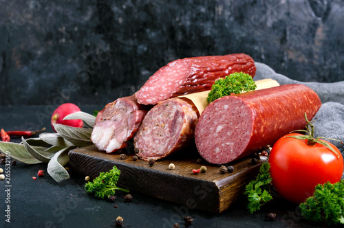 Several kinds of sausage, fresh vegetables and greens on a black background. Products to the holiday.