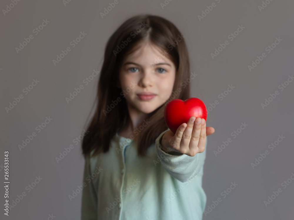 young girl gives a red heart - the concept of childhood, love, relationships, support, health young girl gives a red heart - the concept of childhood, love, relationships, support, health