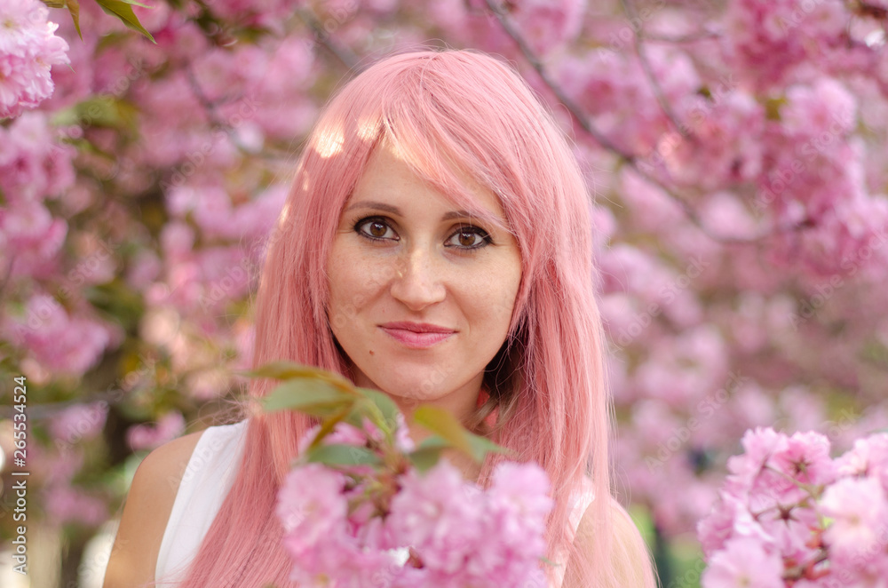 Spring beauty girl with pink hair outdoors. Blooming trees. Romantic young woman portrait. Nature Spring beauty girl with pink hair outdoors. Blooming trees. Romantic young woman portrait. Nature