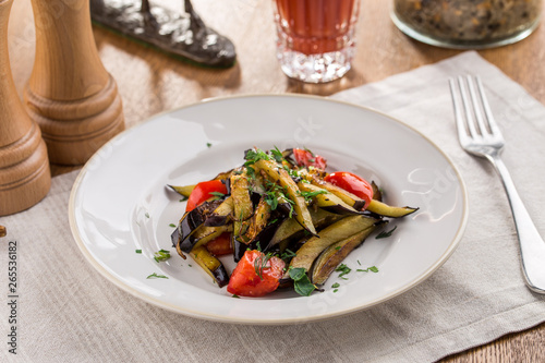 Grilled vegetables warm salad with eggplant and tomato with tomato juice on wooden table