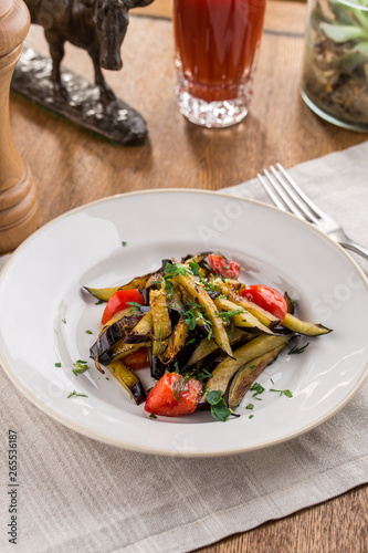 Grilled vegetables warm salad with eggplant and tomato with tomato juice on wooden table