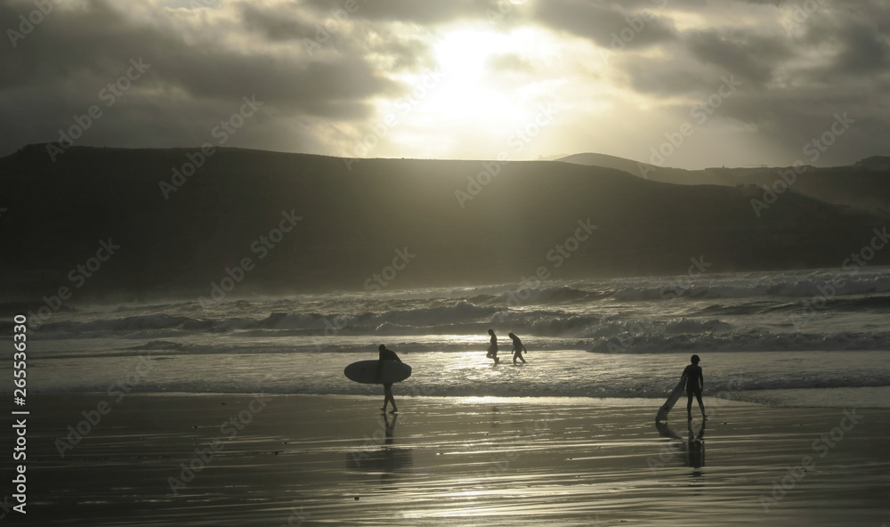group of young surfers in the evening sun on the beach in Las Palmas de Gran Canaria