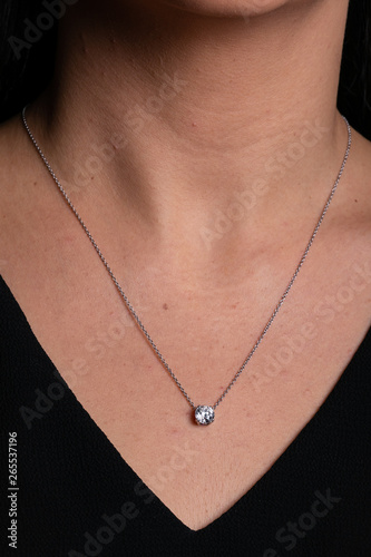 Womens silver chain with a pendant with a stone hanging around his neck.