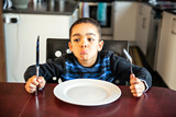 Boy sitting at the kitchen table with empty plate