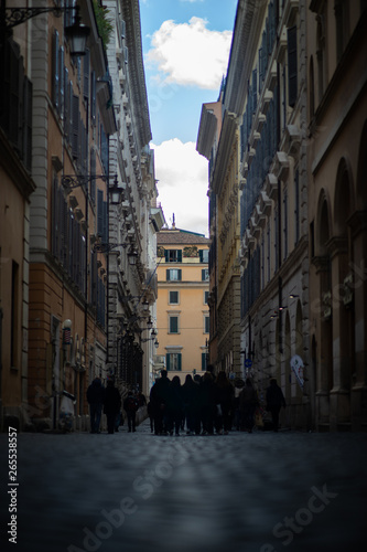 Narrow dark street with people in the center of Rome