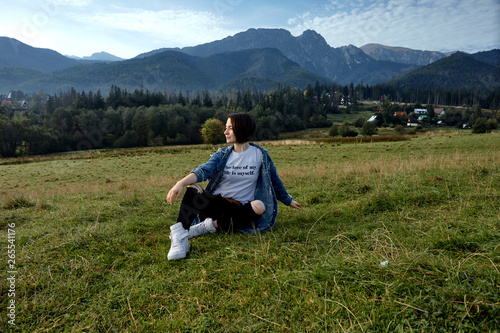 Girl sitting on grass. Mountains as a background