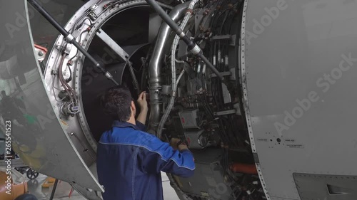 Engineer, technician examines the jet engine with a flashlight. The repair of aircraft in the hangar. Maintenance of aircraft. 4k