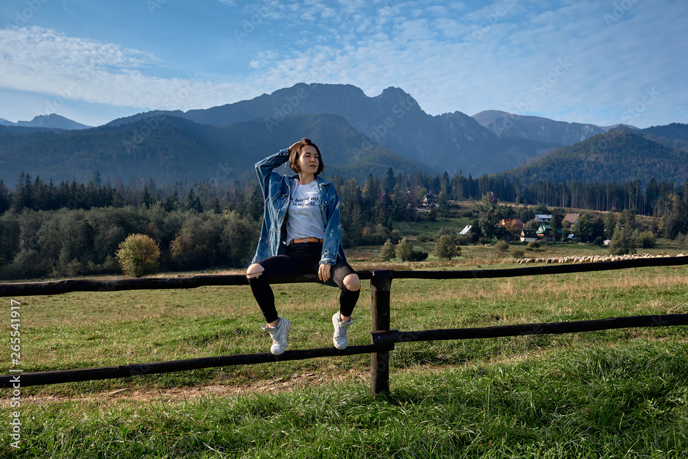 Obraz premium Girl sitting on grass. Mountains as a background