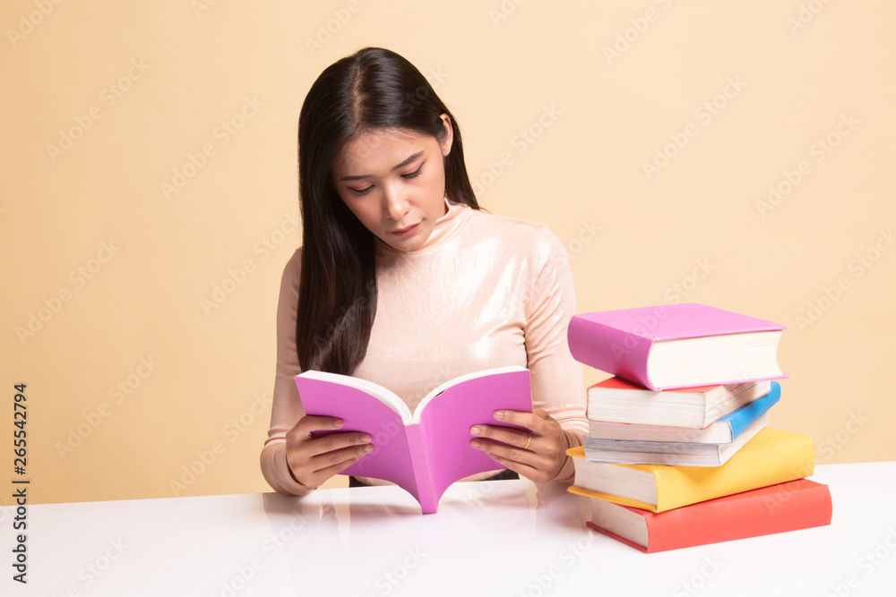 Young Asian woman read a book with books on table. Young Asian woman read a book with books on table.